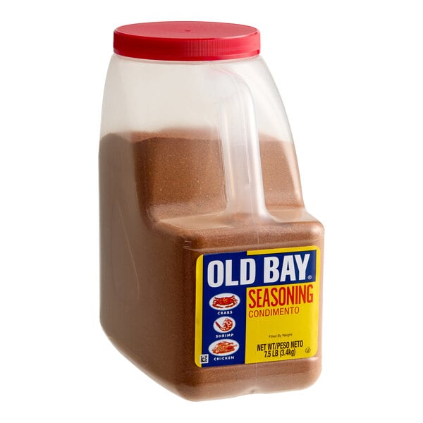 A large plastic container with a red lid, filled with a reddish-brown seasoning and labeled 'OLD BAY SEASONING' on the front.