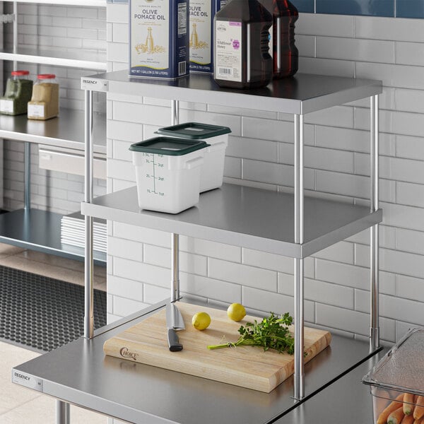 A Regency stainless steel double deck overshelf on a counter over a table with food items on it.