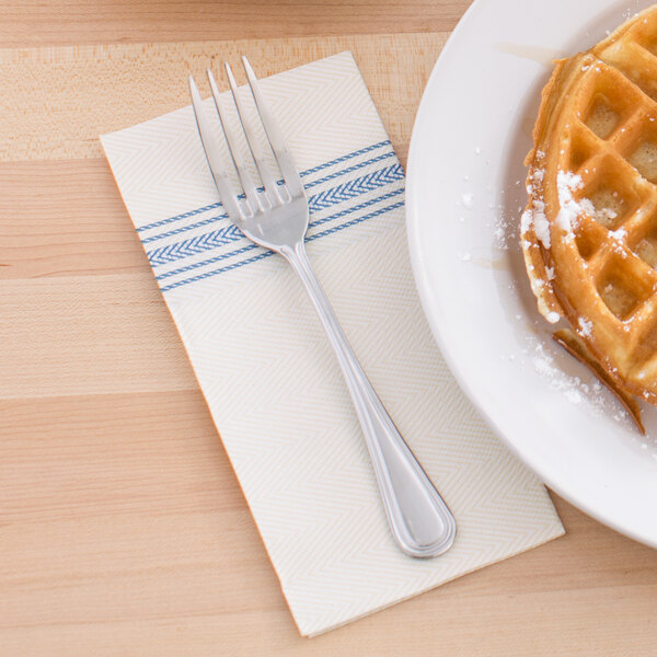 A plate of waffles with a FashnPoint dishtowel print dinner napkin and a fork on it.