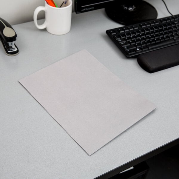 An Oxford gray paper pocket folder on a desk with a piece of paper next to a keyboard.