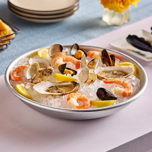 An aluminum tray of seafood on ice with a lemon wedge.