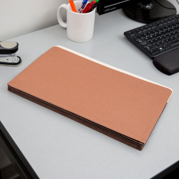 A brown Pendaflex heavy-duty file pocket on a white surface next to a black keyboard.