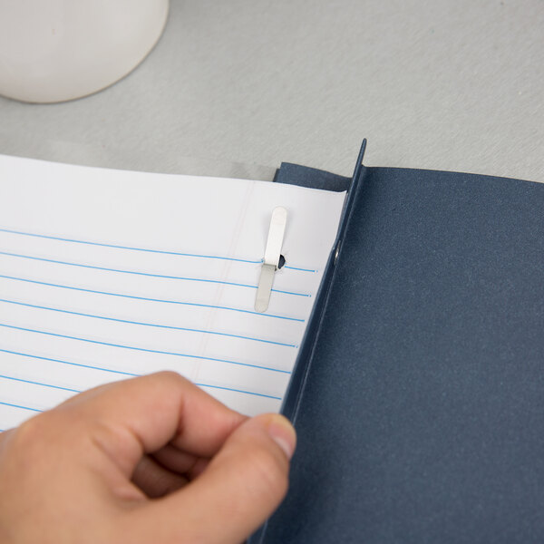 A hand holding a paper with a dark blue Oxford clear front report cover with a paper clip.
