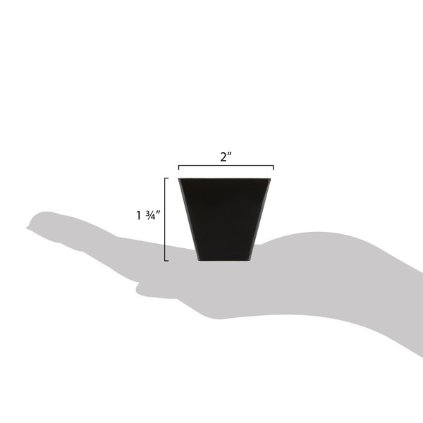 A hand holding a black Fineline Tiny Barware cube bowl.