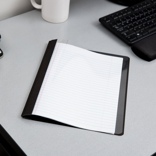 A black Oxford report cover with lined paper on a gray surface.