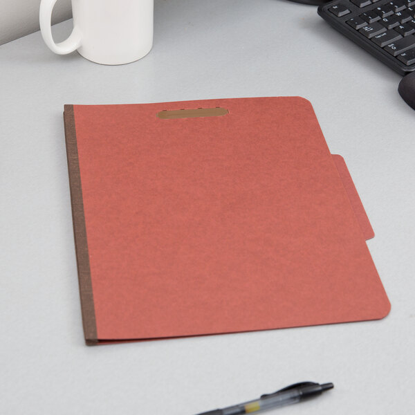 A red Pendaflex classification folder on a desk.