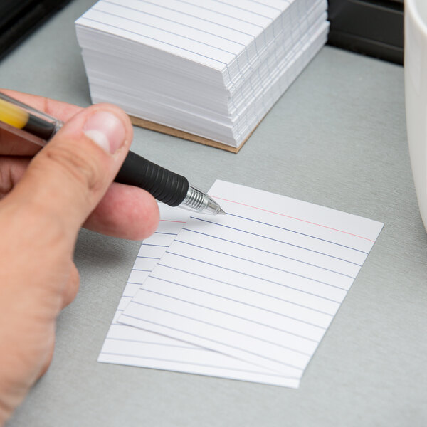 A hand writes on a white Oxford mini index card with a pen.
