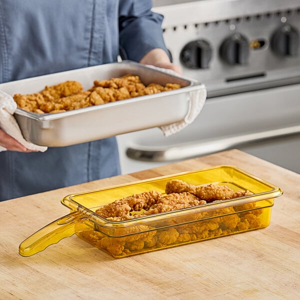 A woman holding a Cambro H-Pan with fried chicken.