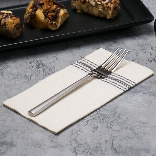 A fork on a Hoffmaster white and black dishtowel print dinner napkin next to food.