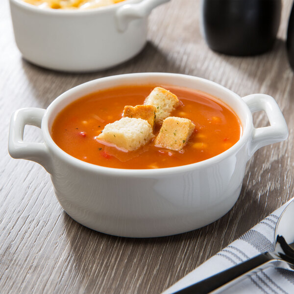 Two white Bon Chef porcelain oval cocottes filled with soup and croutons.