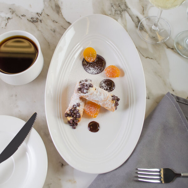 A white Bon Chef porcelain plate with dessert and coffee on a table.