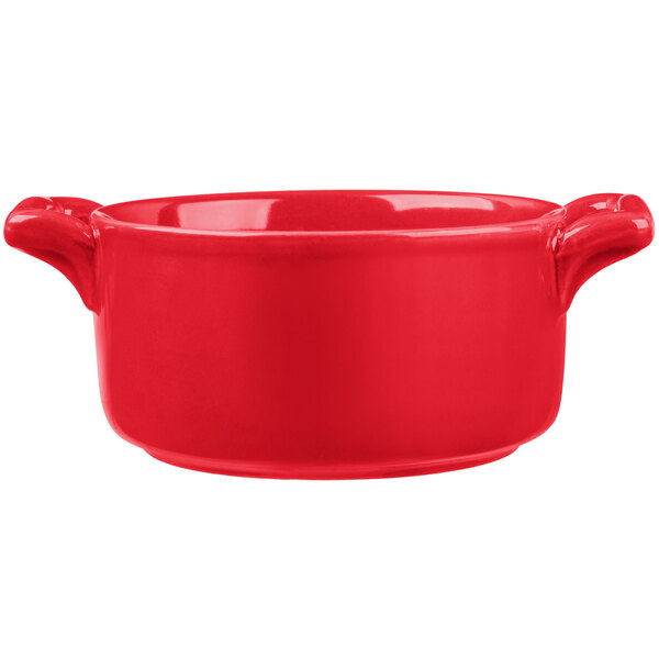 A red porcelain cocotte with handles.