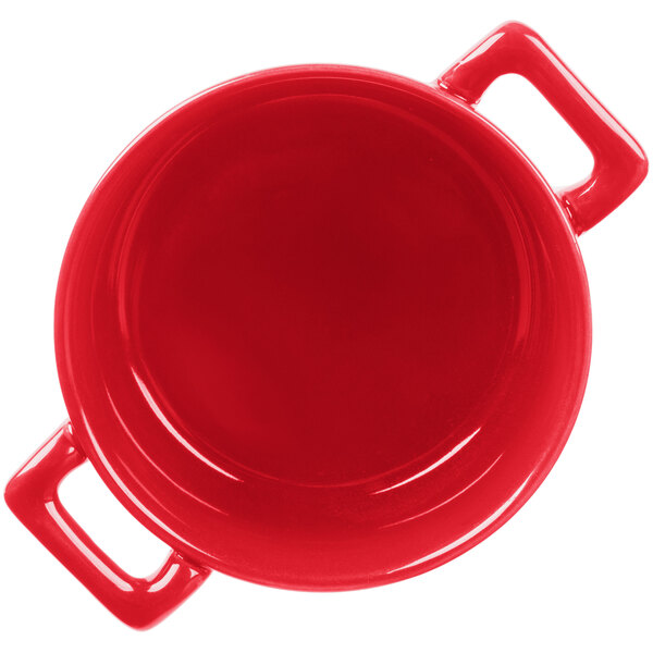 A red porcelain cocotte with two handles.