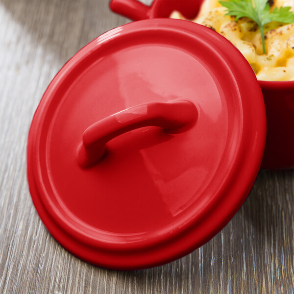 A red Bon Chef porcelain cocotte lid with a handle.