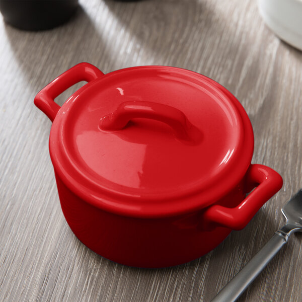 The red Bon Chef porcelain cocotte lid on a red pot with handles.