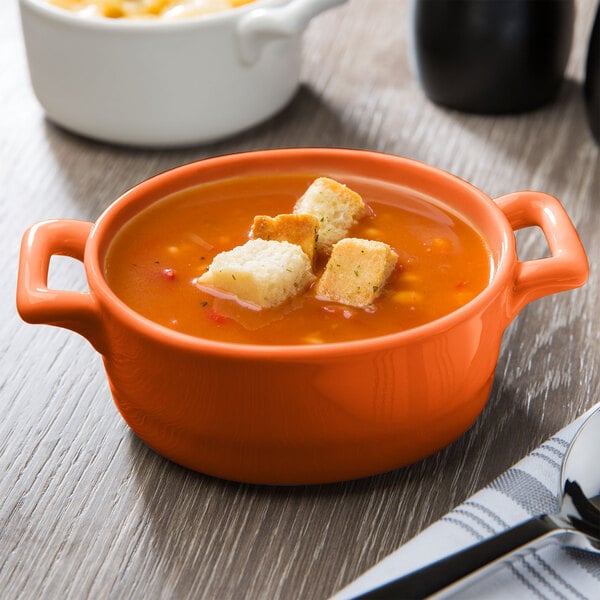 An orange porcelain oval bowl filled with food.