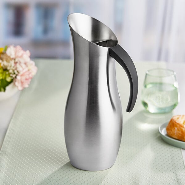 A brushed stainless steel pitcher with a black handle.