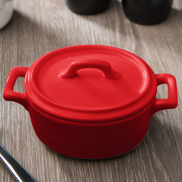 A red porcelain oval cocotte lid on a table.