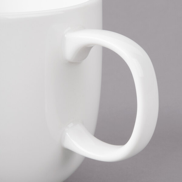 A close-up of a white Bon Chef porcelain cappuccino cup with a handle.