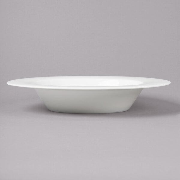 A Bon Chef white bone china wide rim soup bowl on a gray surface.