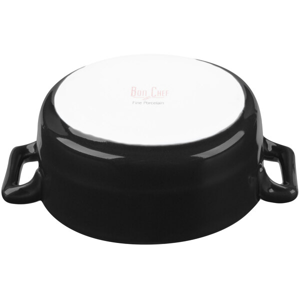 A matte black porcelain Bon Chef oval cocotte with handles and a lid.