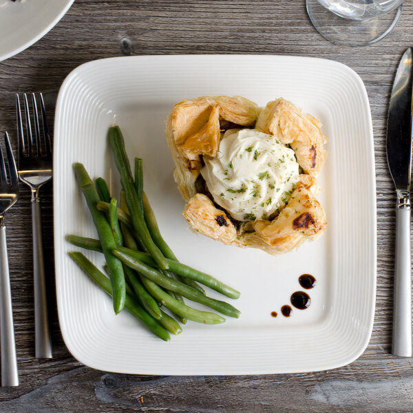 A white Bon Chef porcelain square plate with food on it.