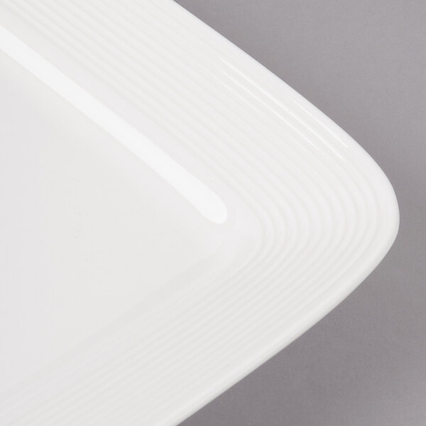 A close-up of a white square porcelain plate with a circle design.