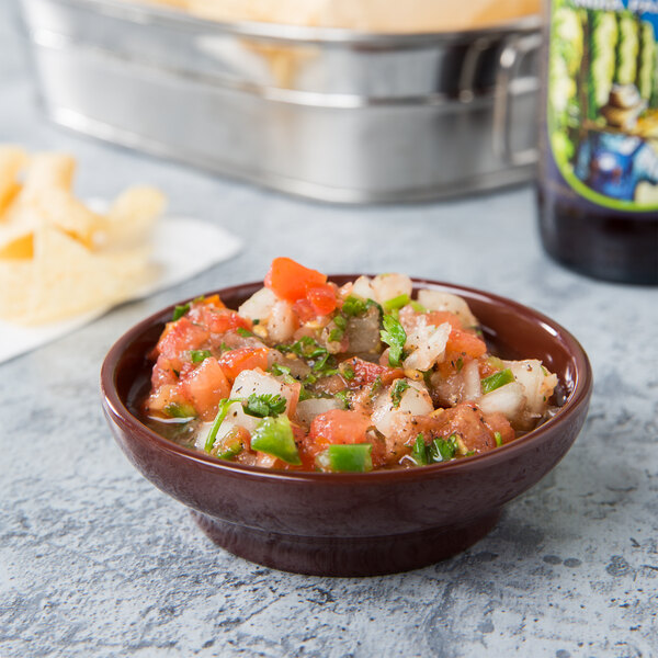 A bowl of salsa with chips in a Thunder Group chocolate melamine bowl on a table.