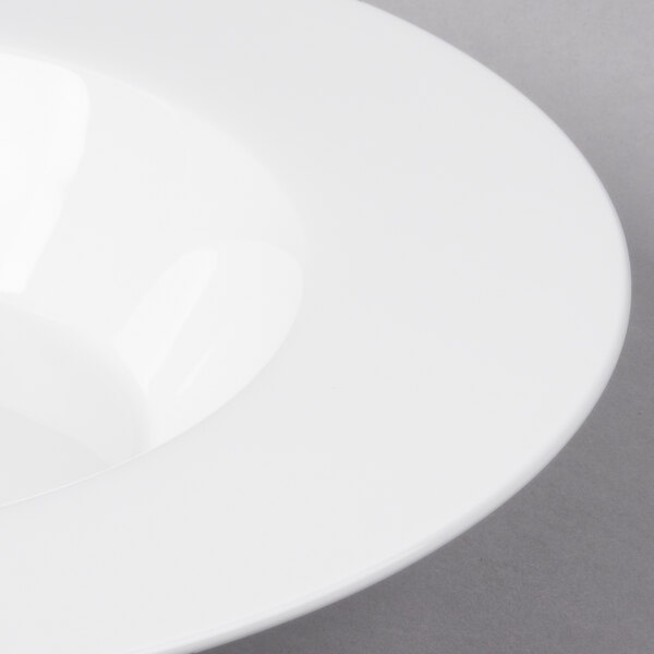 A close-up of a wide rimmed white bone china pasta plate.