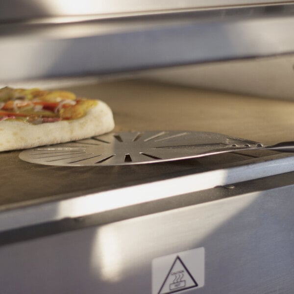A GI Metal round stainless steel pizza peel turning a pizza in an oven.