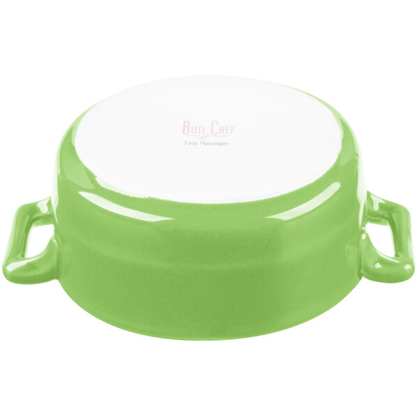 A white porcelain oval cocotte with lime green accents and handles.