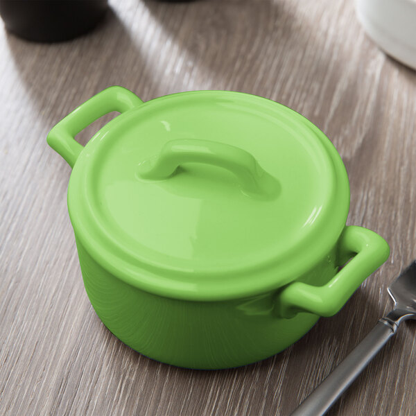 A green Bon Chef porcelain cocotte with a handle and lid.