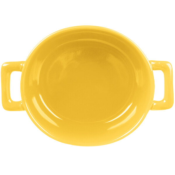 A yellow porcelain oval cocotte with handles.
