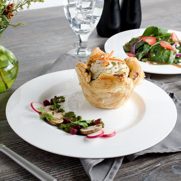 A Bon Chef white bone china dinner plate with a pastry and a fork on it on a table.