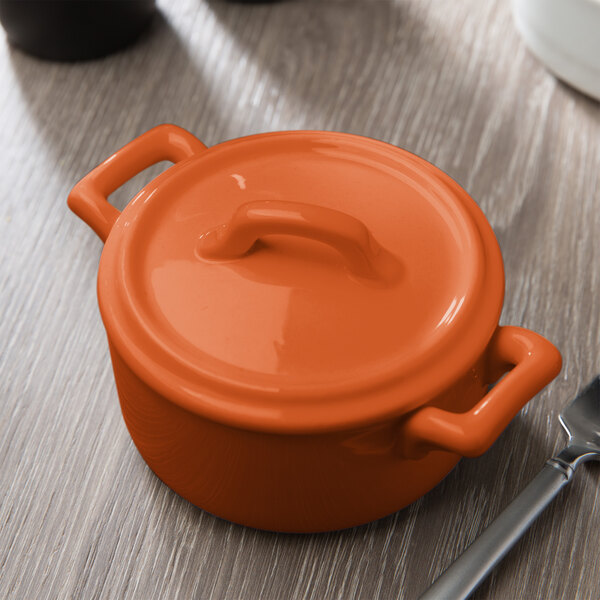 The orange lid of a small Bon Chef porcelain casserole dish.