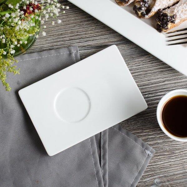 A white Bon Chef bone china demi saucer on a table with a cup of coffee and food.