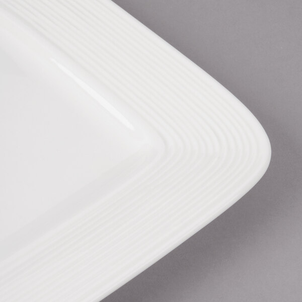 A close-up of a white rectangular porcelain plate with circles on the edge.