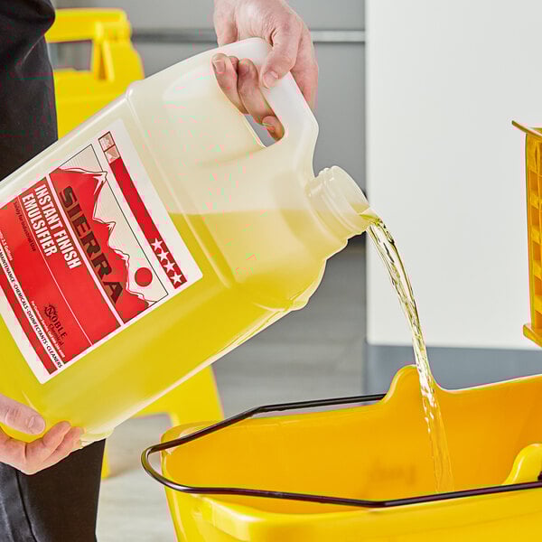 A person pouring yellow Sierra by Noble Chemical liquid into a bucket.