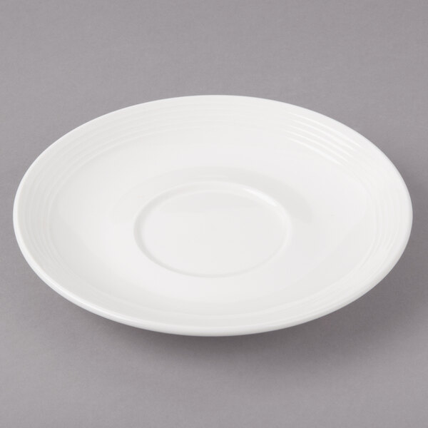 A white porcelain saucer with a circular pattern on the edge.