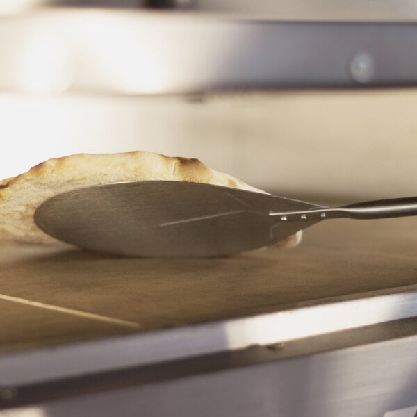 A pizza being put in a toaster oven on a GI Metal stainless steel pizza peel.