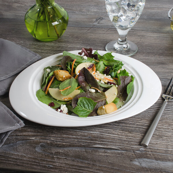 A Bon Chef white porcelain oval salad plate with salad and a fork on it.