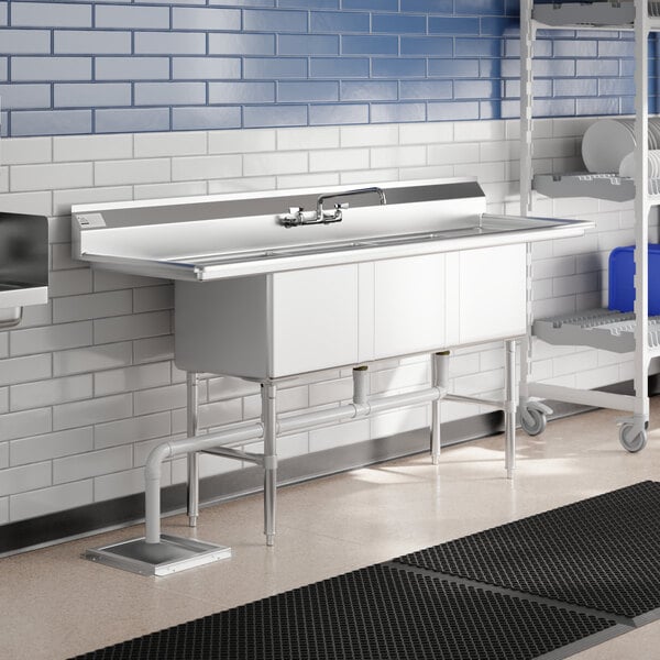A stainless steel Advance Tabco three compartment sink with two drainboards.