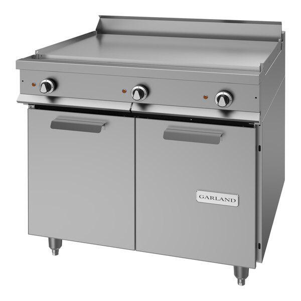 A heavy-duty electric range with a griddle top and storage base, made of stainless steel.