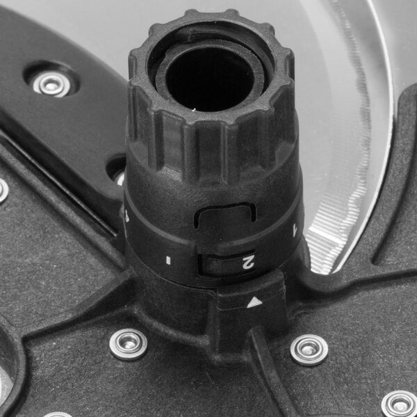 A close-up of a black and white metal Waring slicing disc.