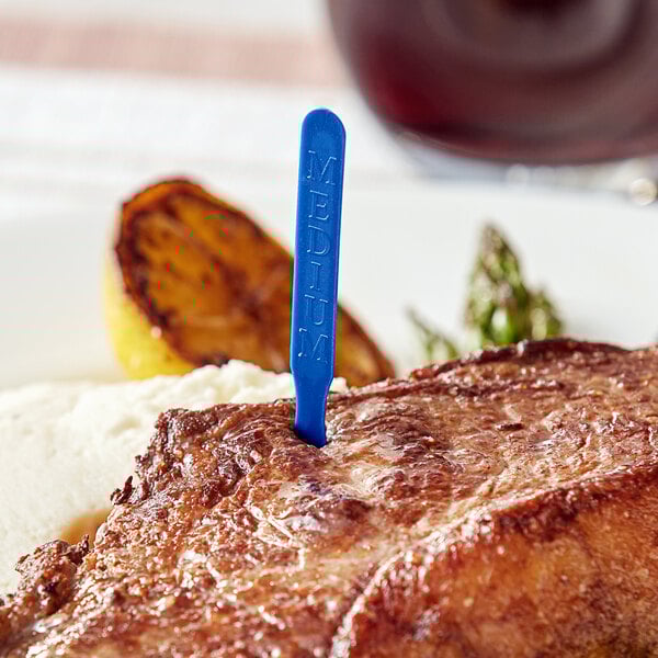 A piece of steak with a blue plastic steak marker in it.