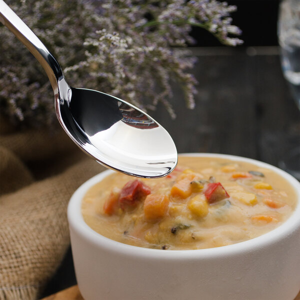 A Walco stainless steel bouillon spoon over a bowl of soup.