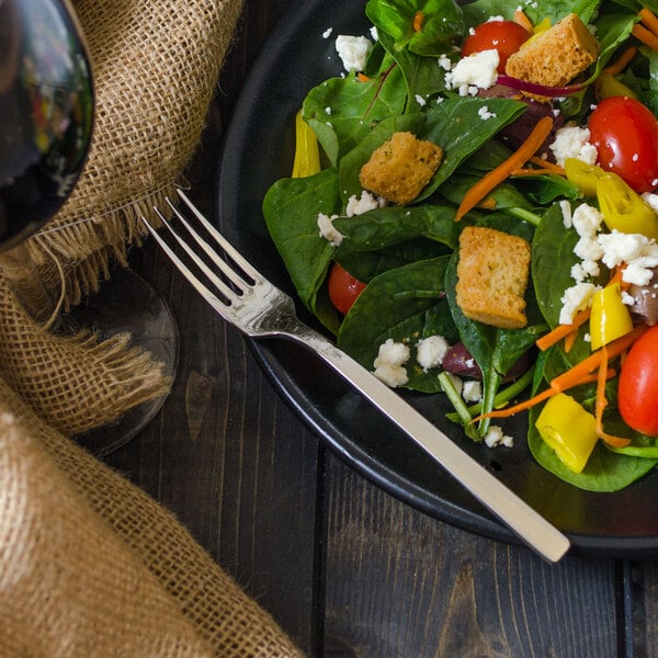 A plate of salad with a Walco stainless steel salad fork next to it.