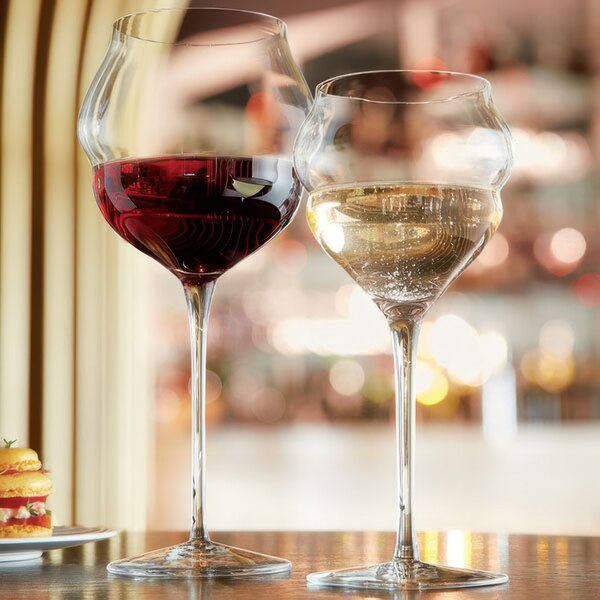 Two Chef & Sommelier wine glasses on a table with a glass of red wine.