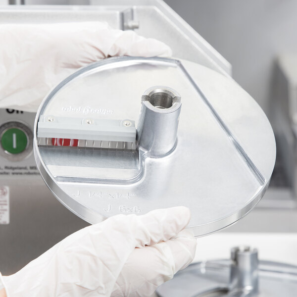 A person in white gloves holding a circular metal disc.