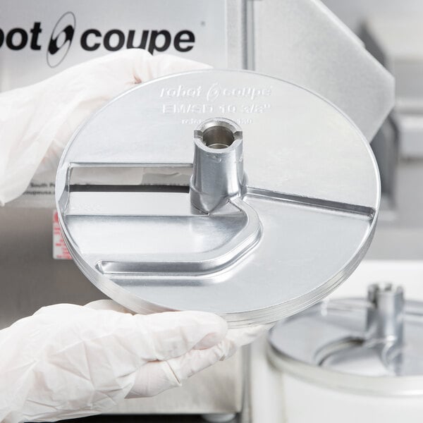 A person in gloves using a Robot Coupe LP5DISC metal disc.
